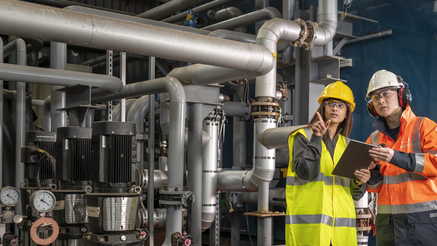 Technicians standing in front of industrial piping